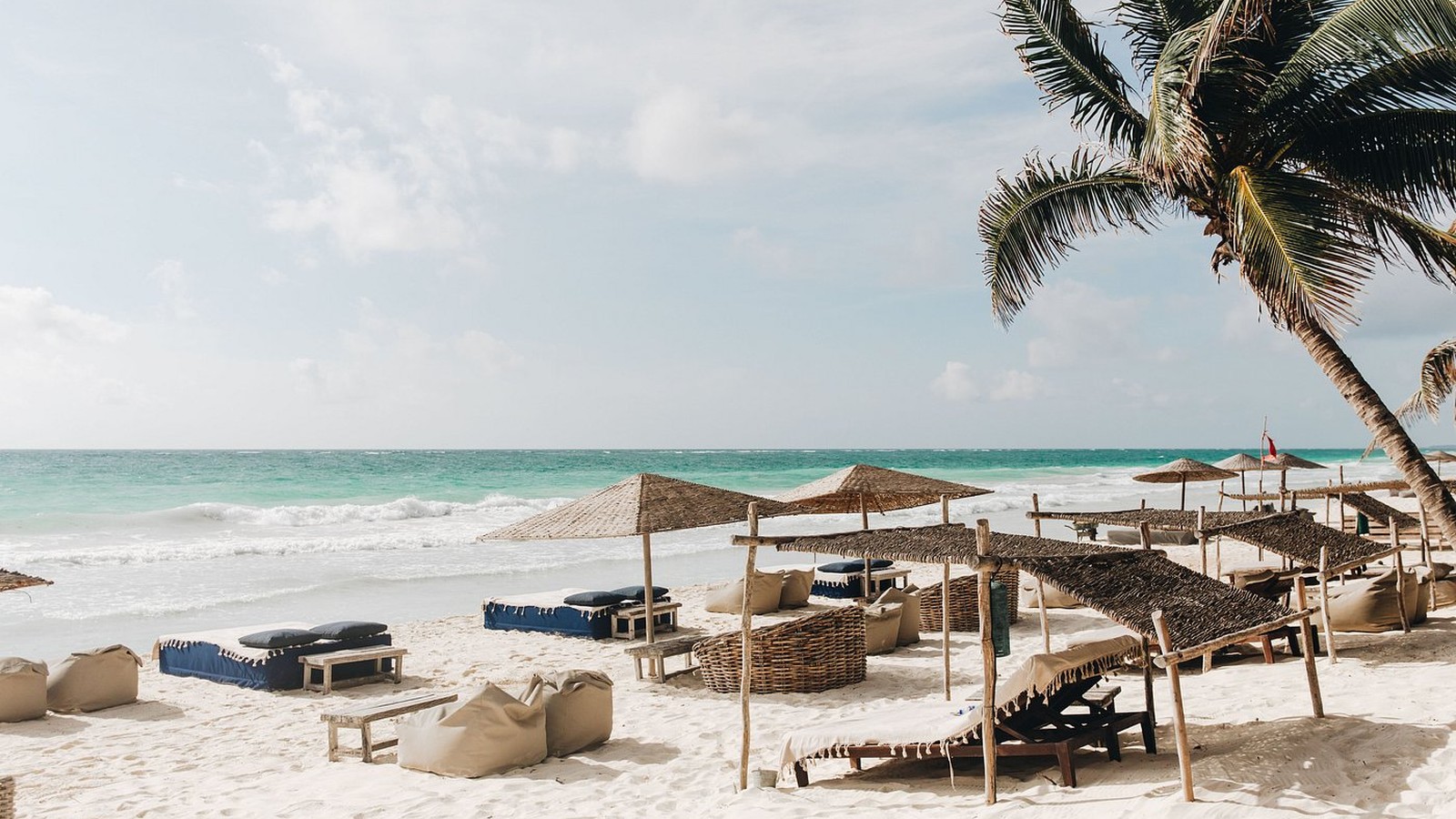 Be Tulum beachfront boutique hotel scene with palm shade and Caribbean water in Tulum