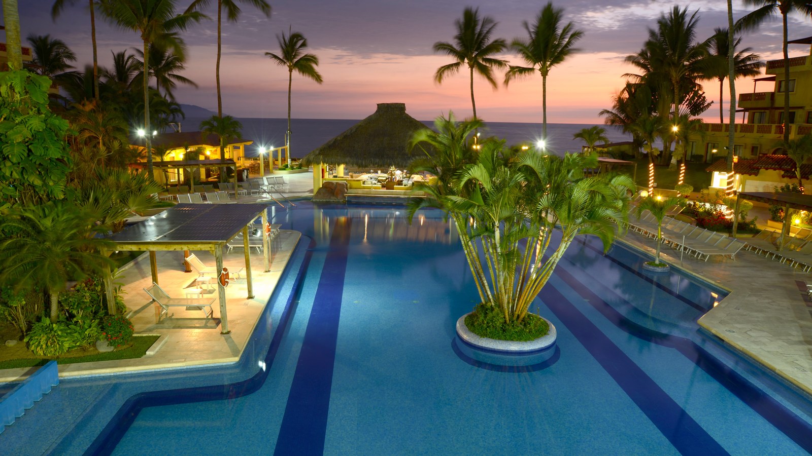 Canto Del Sol resort pool in Puerto Vallarta at sunset with palms and ocean views