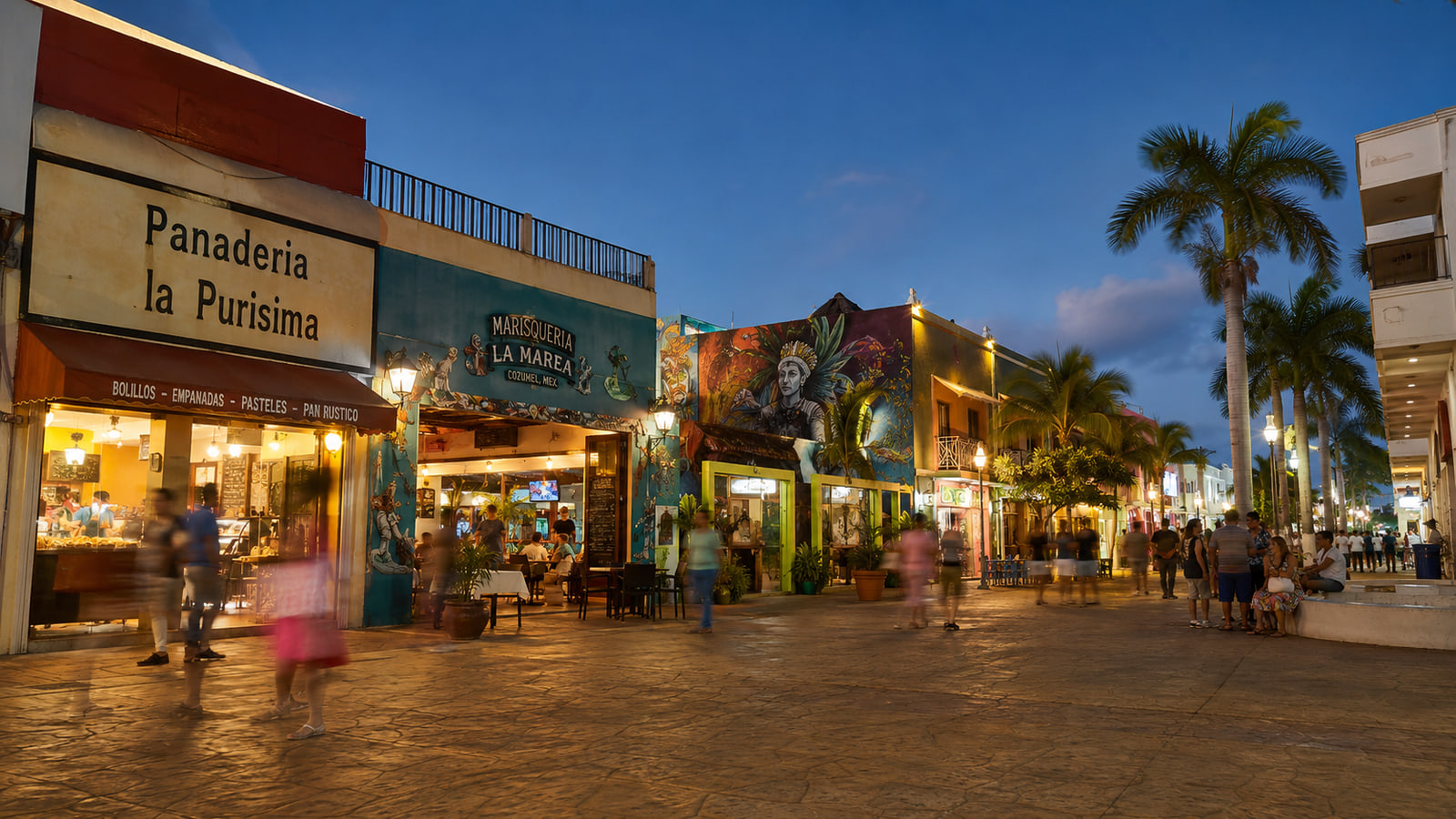 Shops, restaurants, murals, and visitors in central San Miguel de Cozumel at dusk